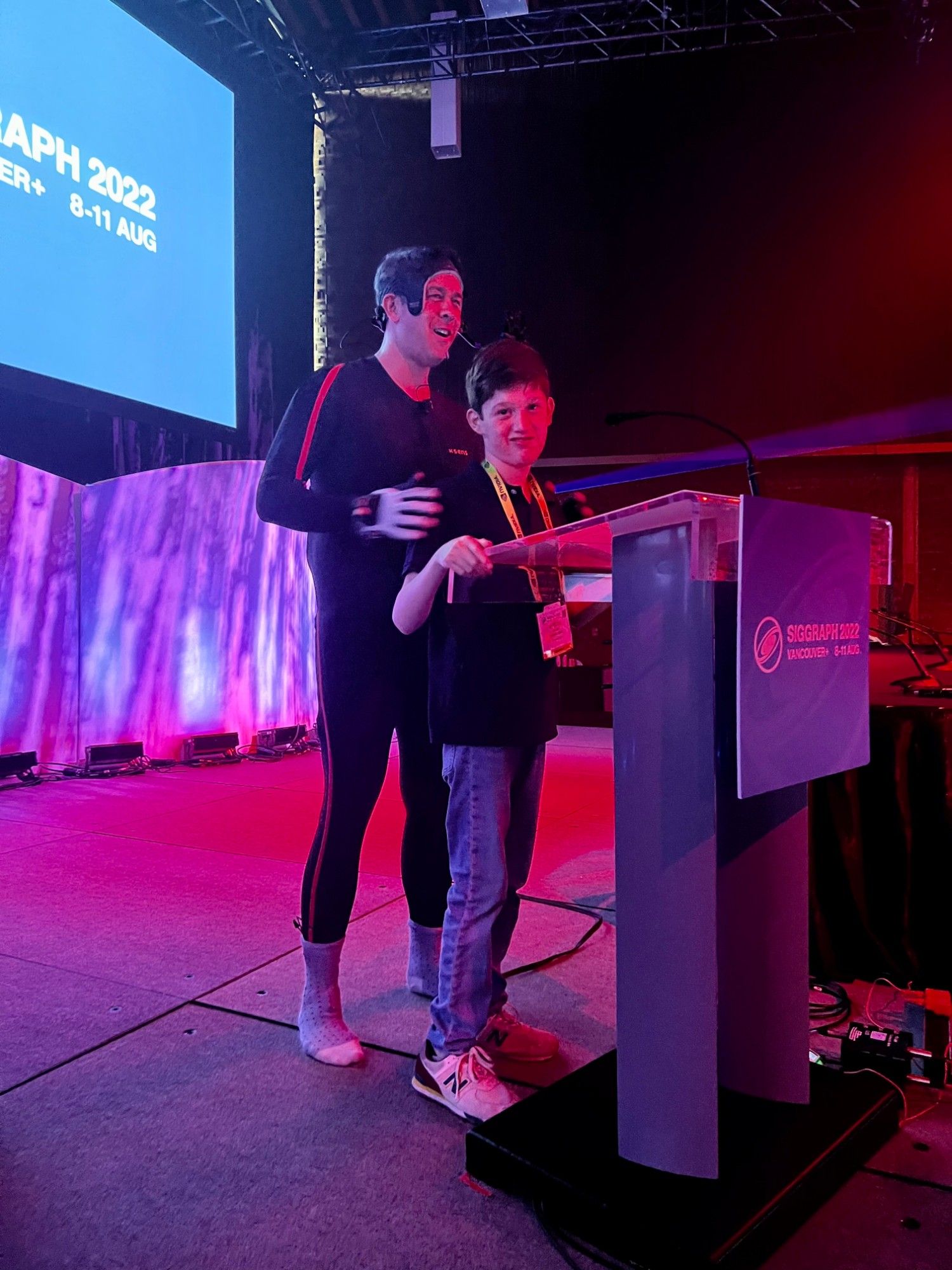 Darin Grant in a motion-capture suit on stage with his son Atticus at SIGGRAPH 2022