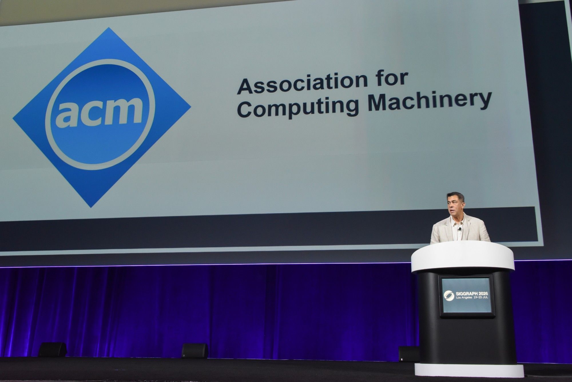 Darin Grant, as ACM SIGGRAPH Chair, speaking on the main stage of SIGGRAPH 2026 in Los Angeles